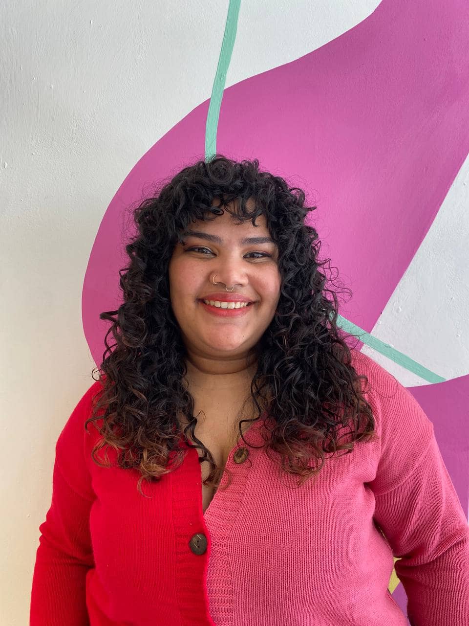 Mujer de frente sonriendo y mostrando su corte de cabello en capas y con flequillo