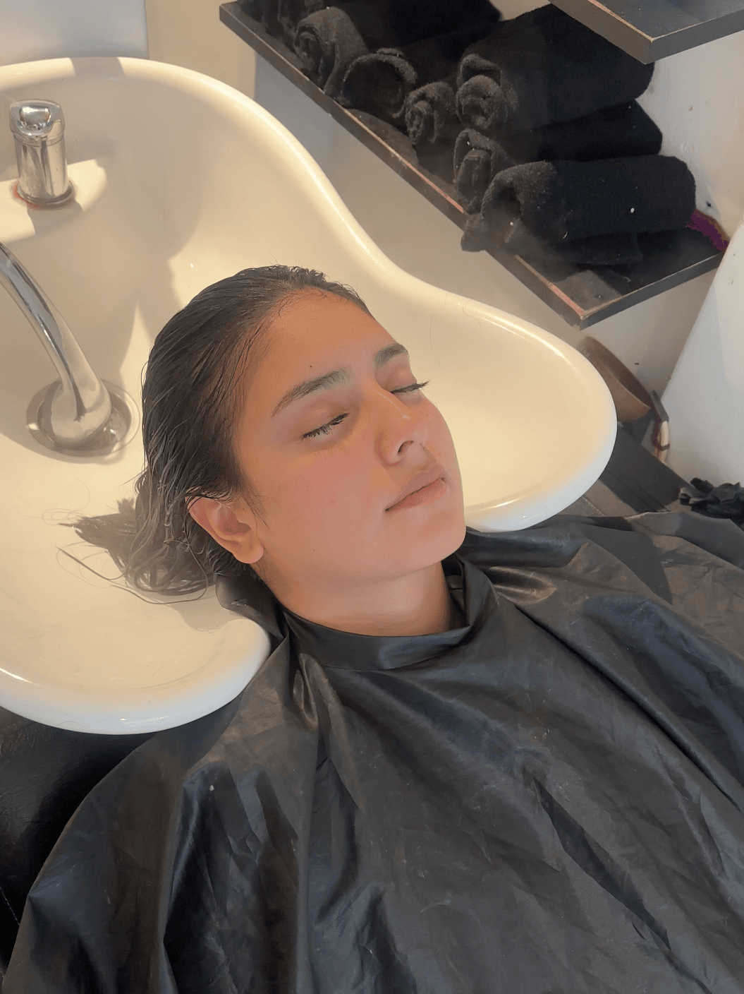 Mujer acostada en lavacabezas disfrutando del servicio de tratamiento profundo con ozonoterapia