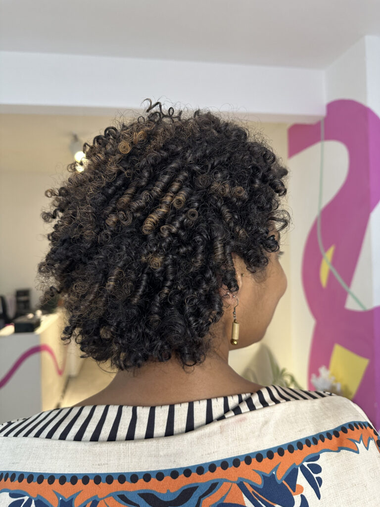 Mujer de espaldas mostrando afro con algunas iluminaciones claras