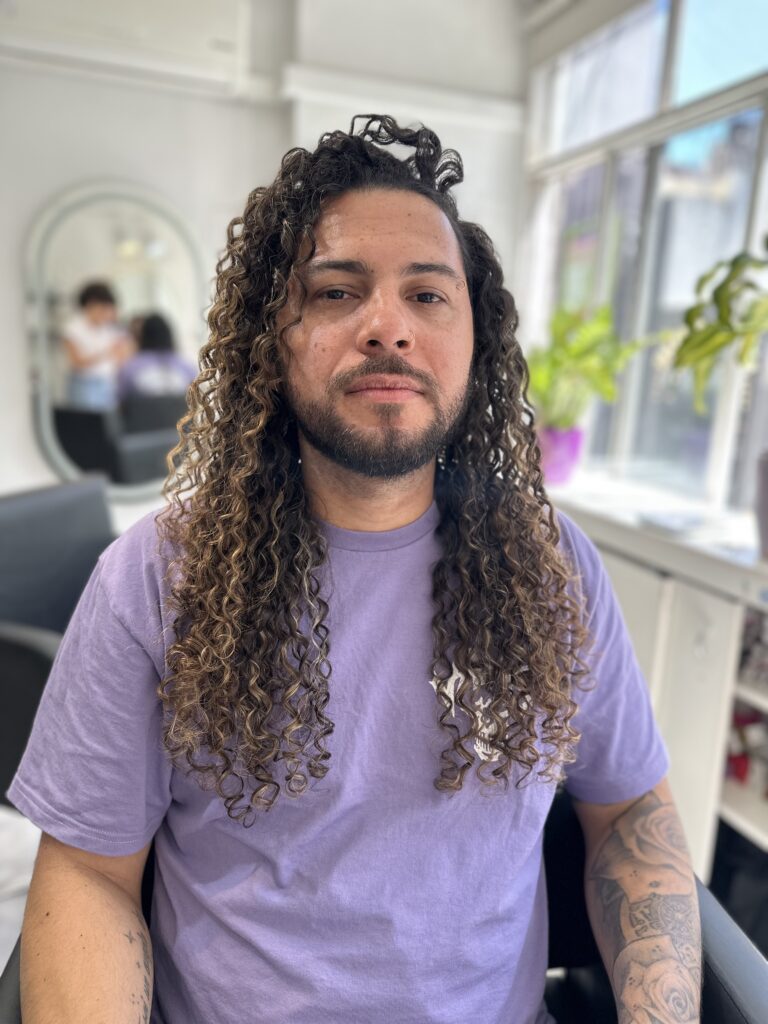 Hombre de frente con el cabello largo mostrando iluminaciones rubias en cabello castaño